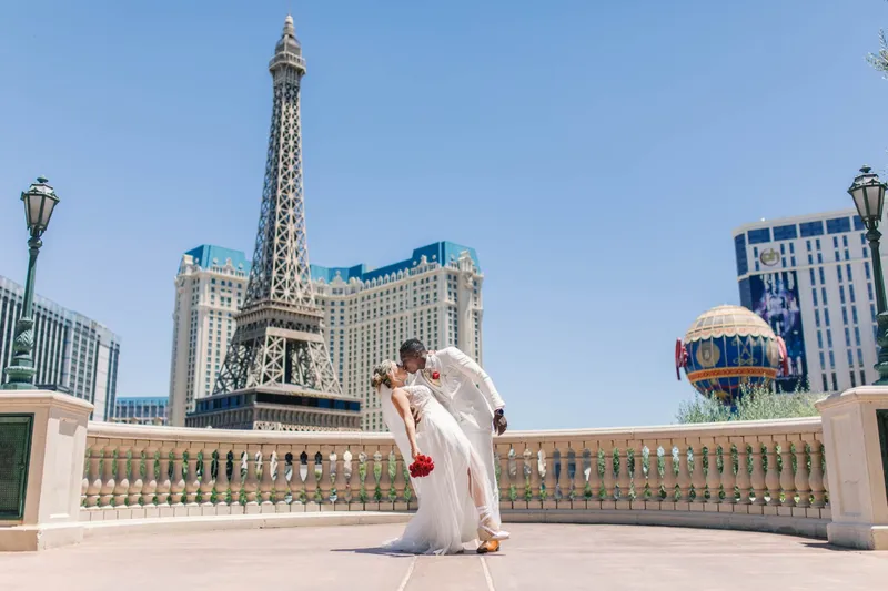 The two of them kissing at the curved stone railing with the Eiffel Tower off to one side