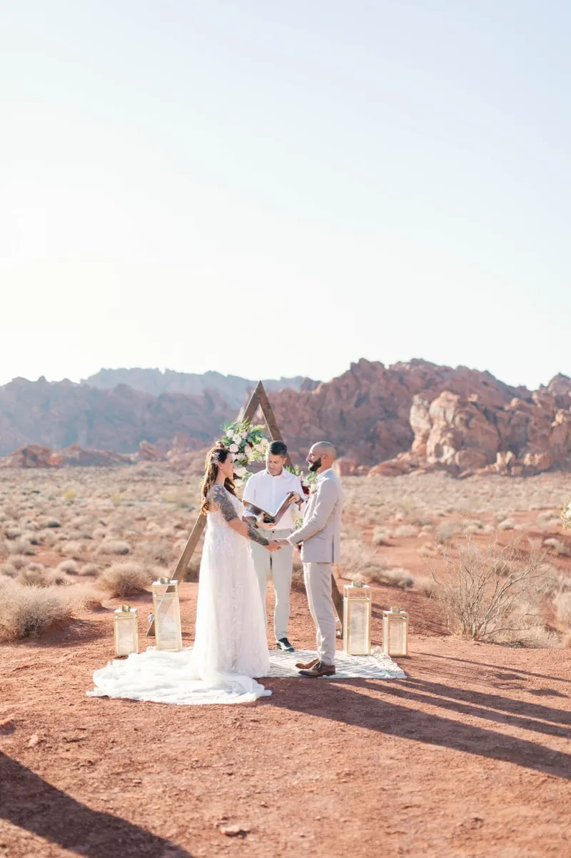 Bride and groom exchanging rings beneath the flower topped arch