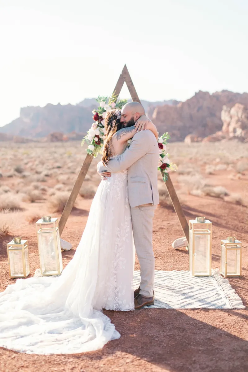 Bride and groom kissing at the arch with the red rock towers behind them