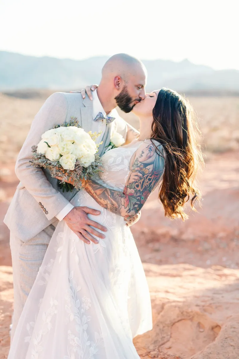 A groom dipping his bride for a kiss among the red rocks at Valley of Fire