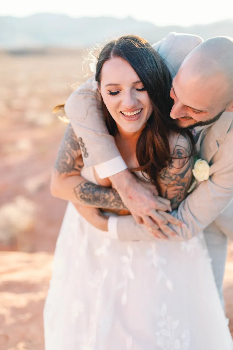 Bride smiling with her eyes closed while her groom holds her close