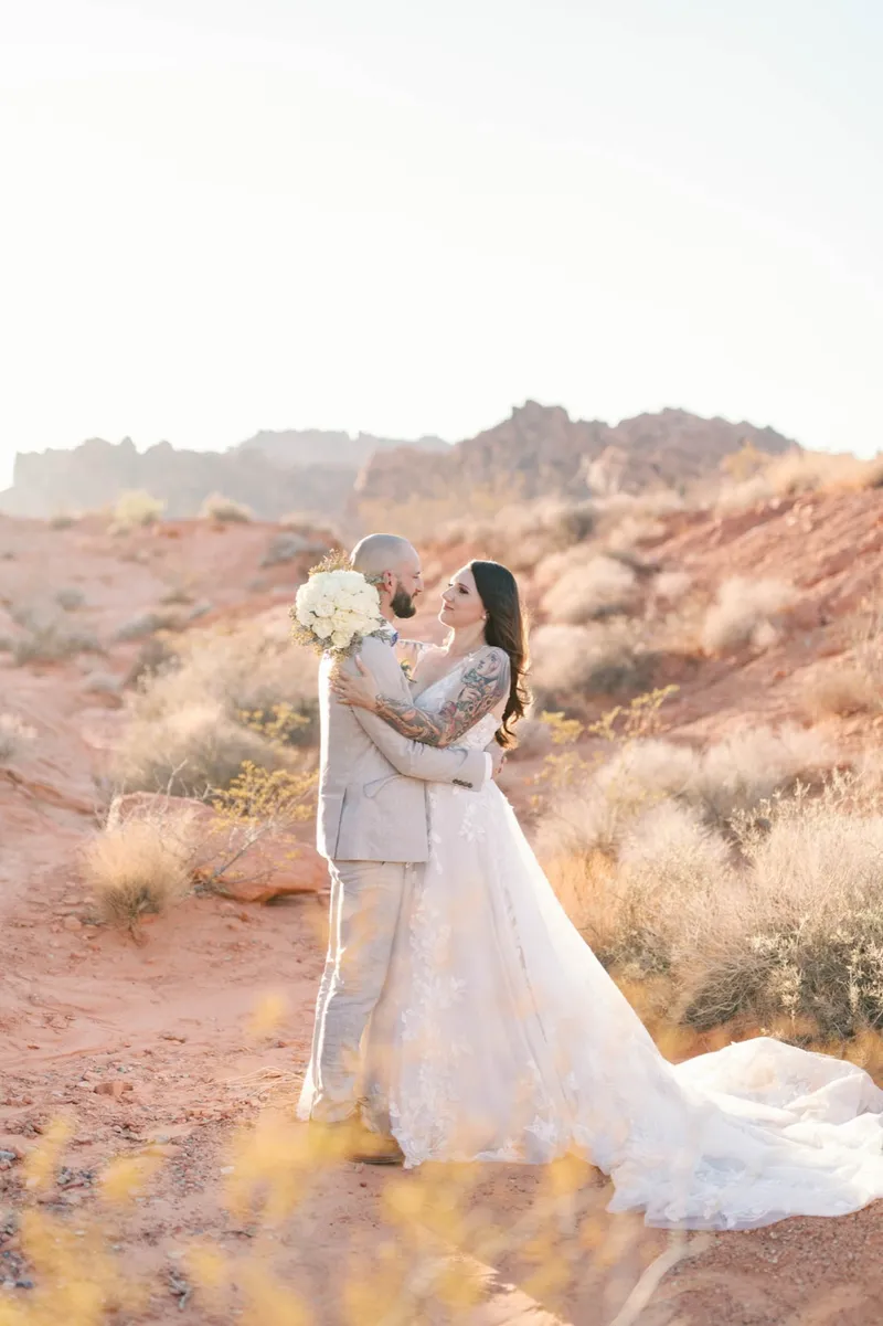 Couple kissing among the desert brush with the pale cliffs beyond