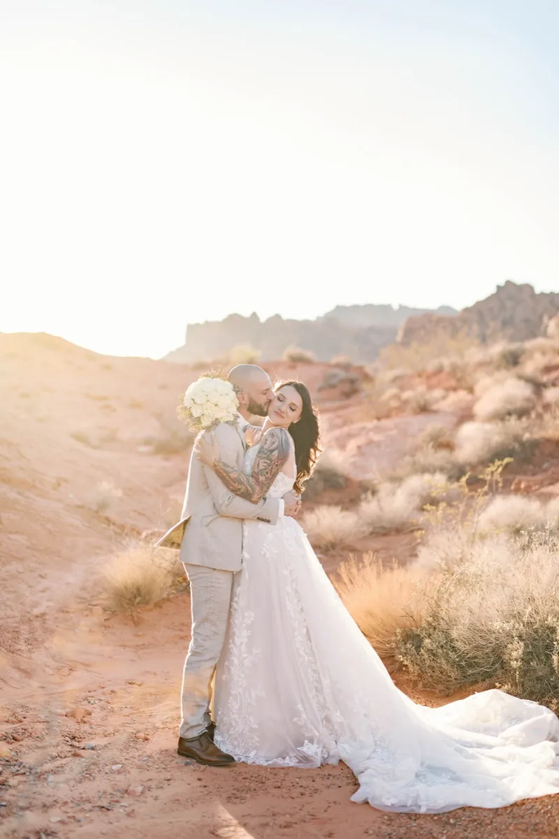 Couple holding each other in the last light with the red rock washed gold