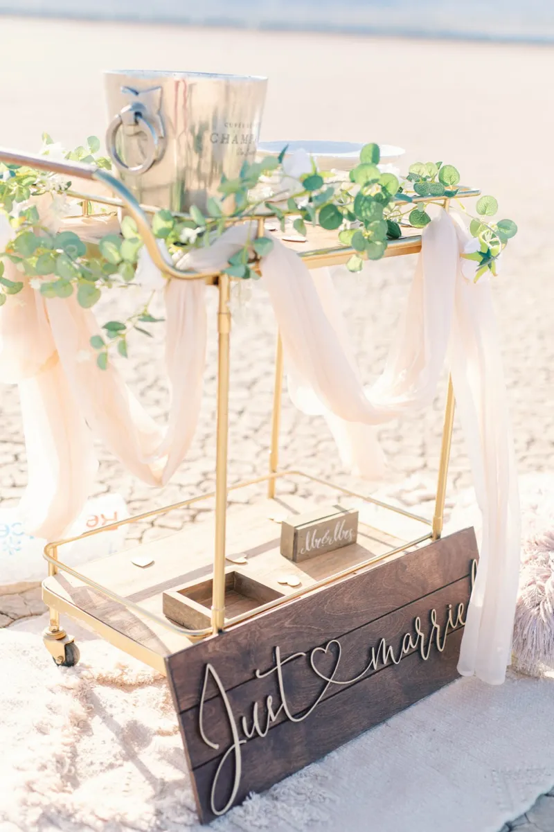 Draped gold arbor with a wooden just married sign and the ring box set out on the lake bed