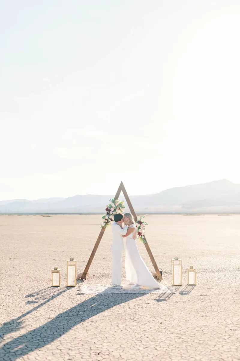Bride walking the long open aisle toward the arch with gold lanterns lining the way