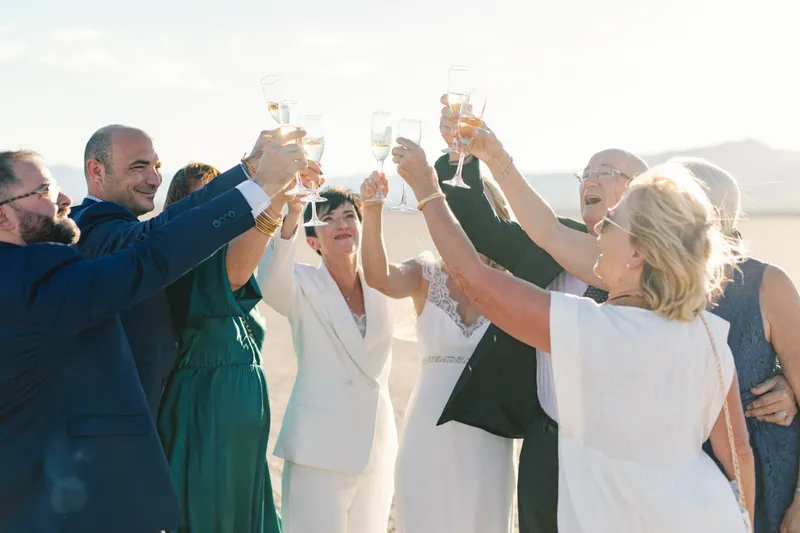 Guests raising champagne glasses together in a toast out on the lake bed