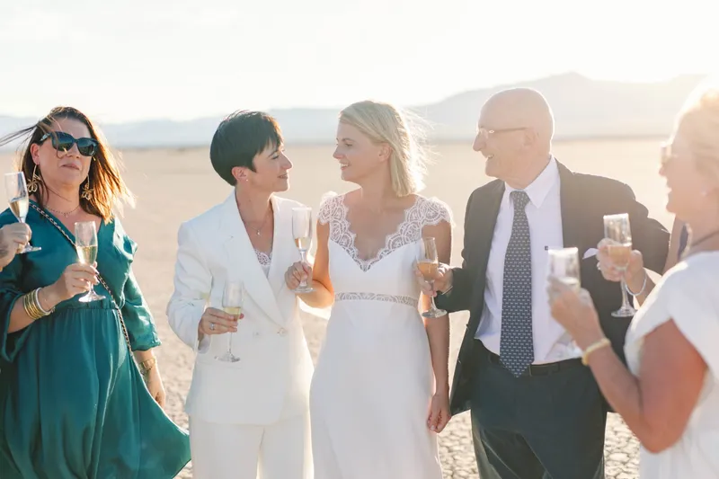 Two brides toasting champagne with an older couple at their lake bed celebration