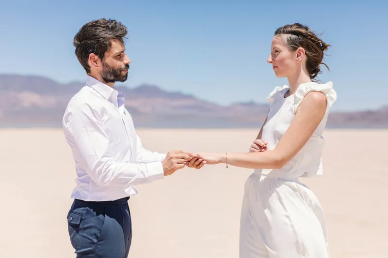 Bride and groom facing each other and holding hands during their vows, mountains soft behind them