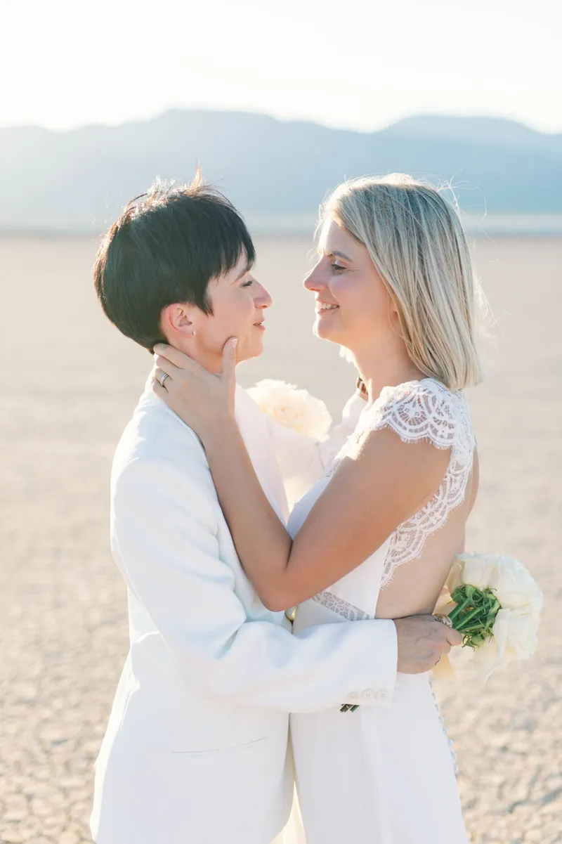 Two brides holding each other close with their bouquets still in hand