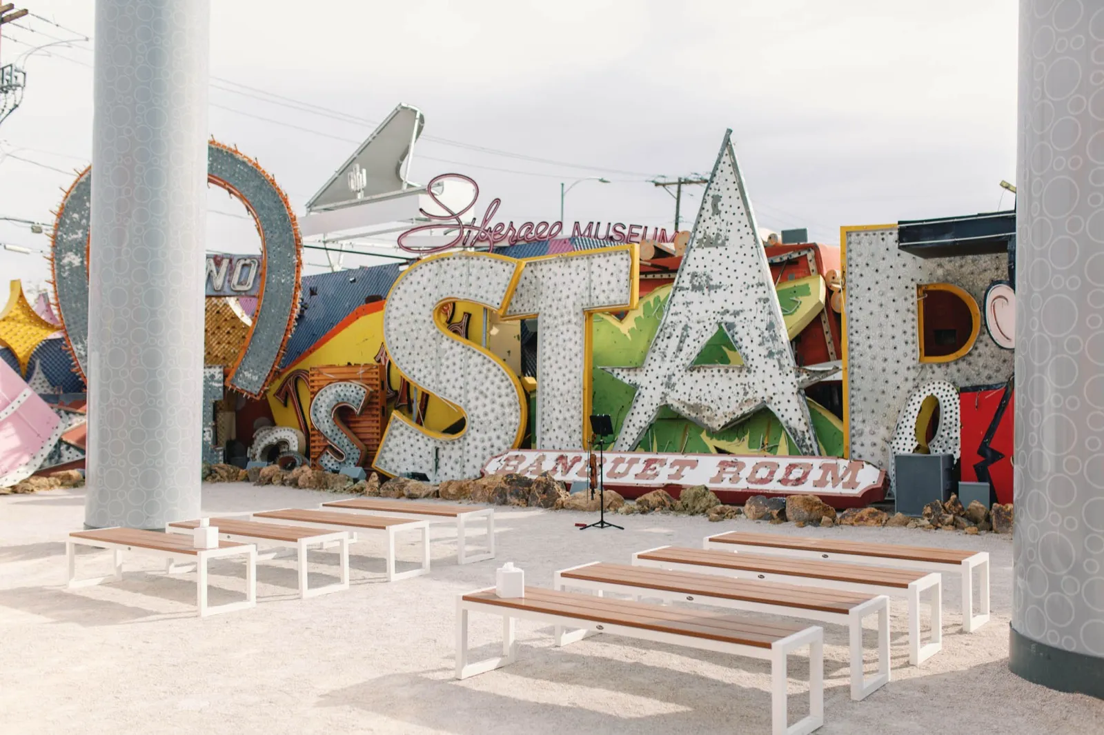 Wooden benches set on gravel facing the giant unlit Stardust letters and rows of salvaged casino signs