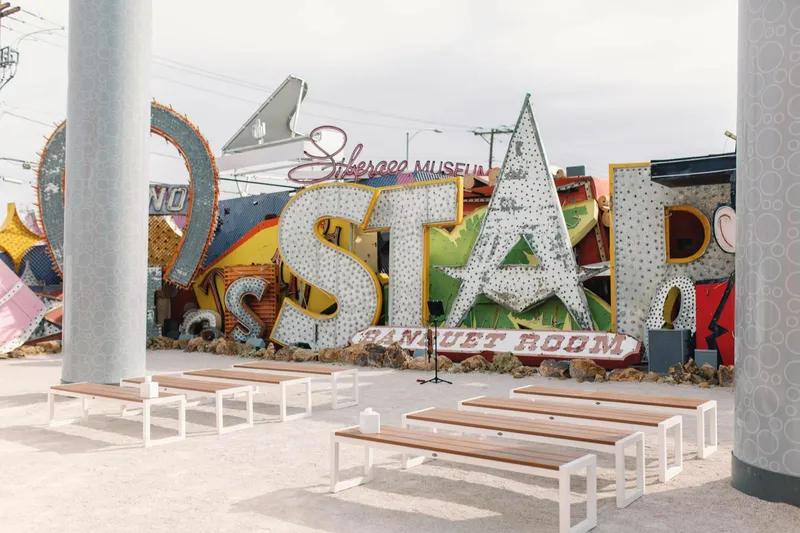 Rows of old casino signs in the boneyard with white benches set up for a ceremony