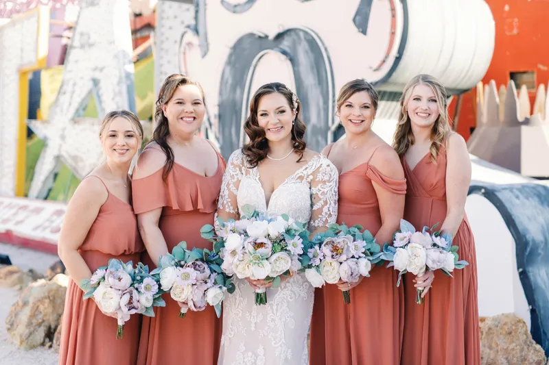 The bride laughing with her full line of bridesmaids among the salvaged neon