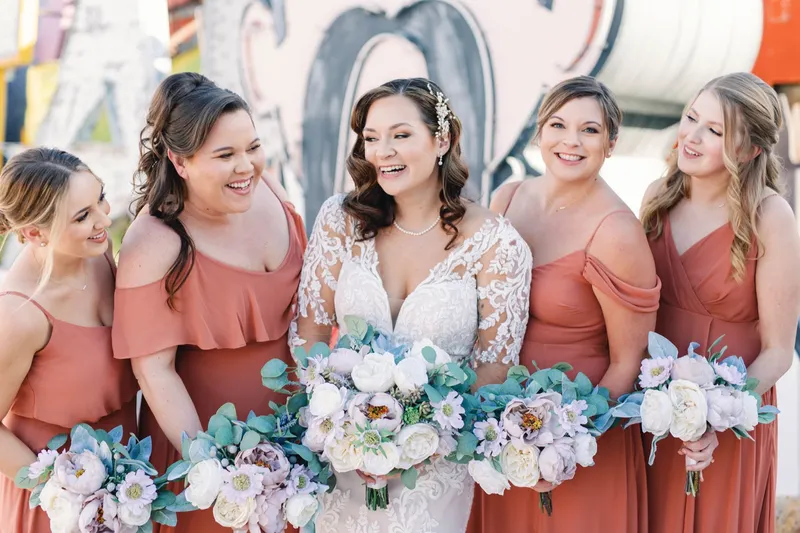 Bride and two bridesmaids laughing together with their bouquets raised