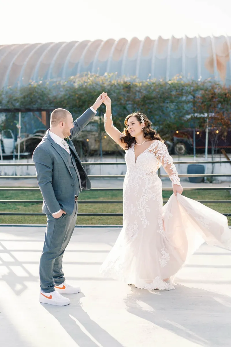 Bride sweeping her skirt out to the side with her hand still in the groom's, both of them in the last of the low sun