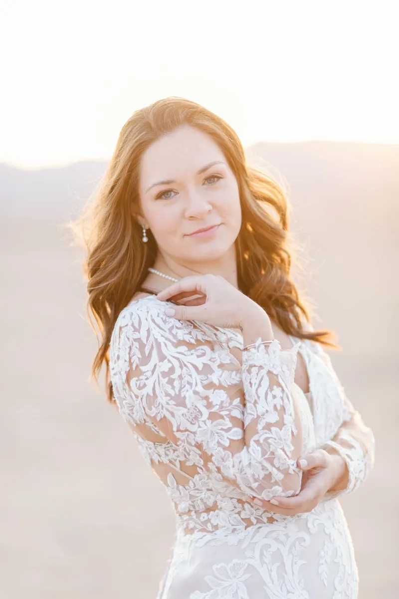 Portrait of a red haired bride in a long sleeve lace gown on the open lake bed