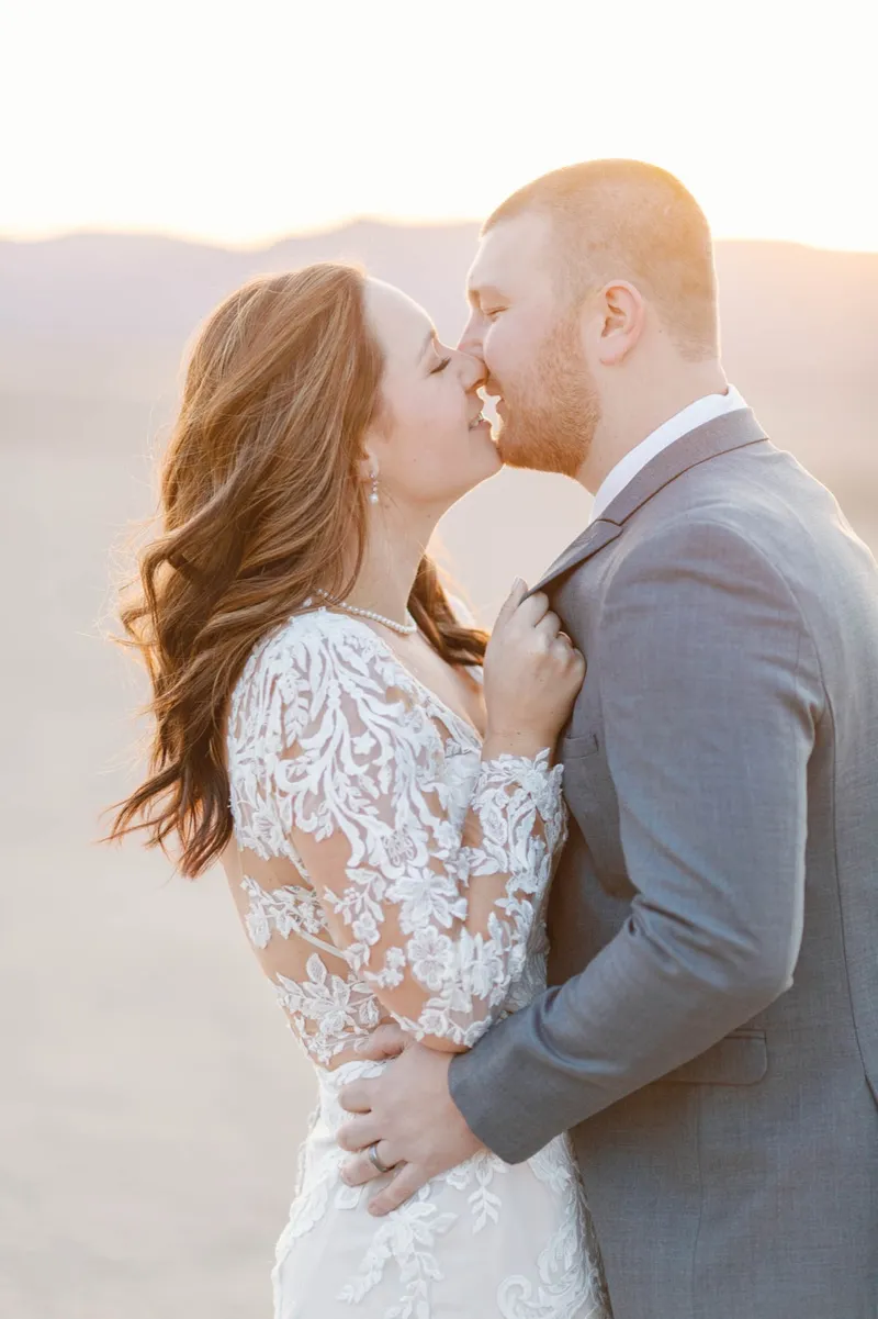 A bride and groom kissing at sunset on the dry lake bed outside Las Vegas