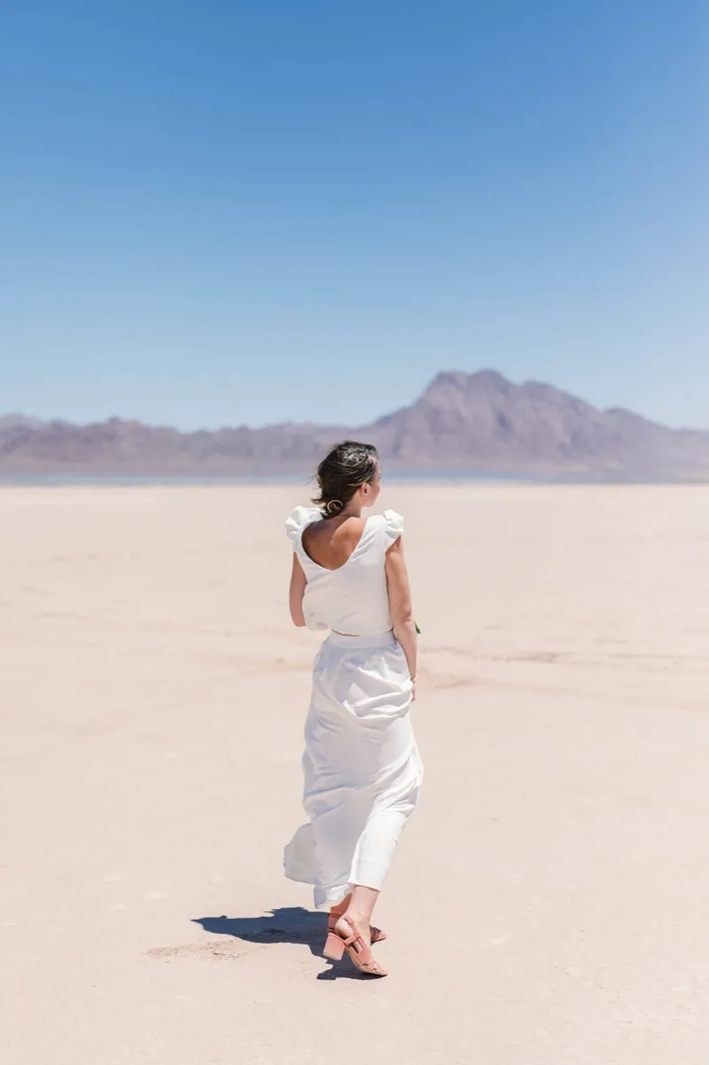 Bride in a satin gown looking back over her shoulder with a single peak rising behind her
