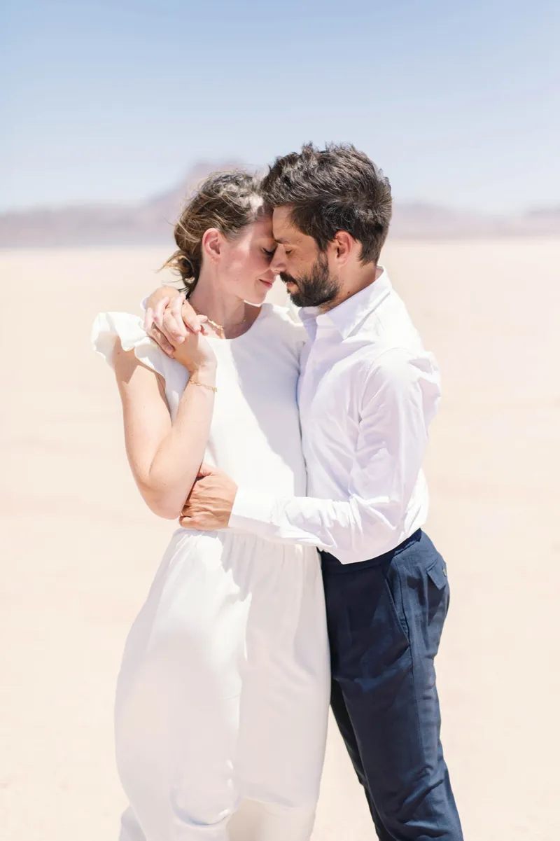 Newlyweds standing forehead to forehead with their eyes closed in the middle of the open desert