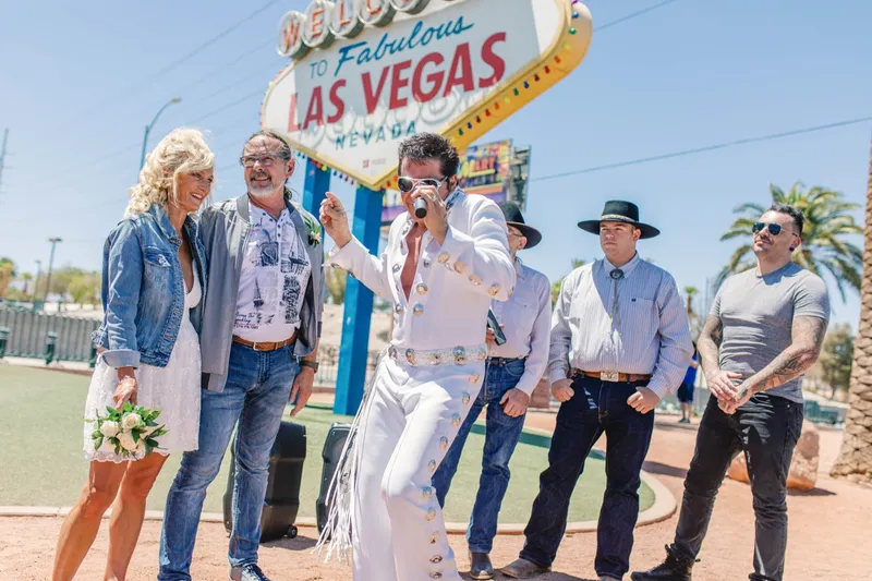 Elvis officiant performing with a microphone for the small group at the sign