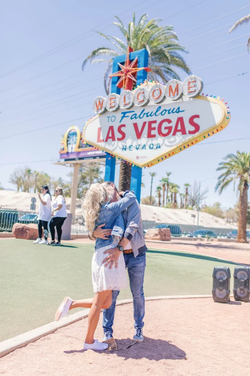 The couple laughing with their guests after the ceremony in front of the sign