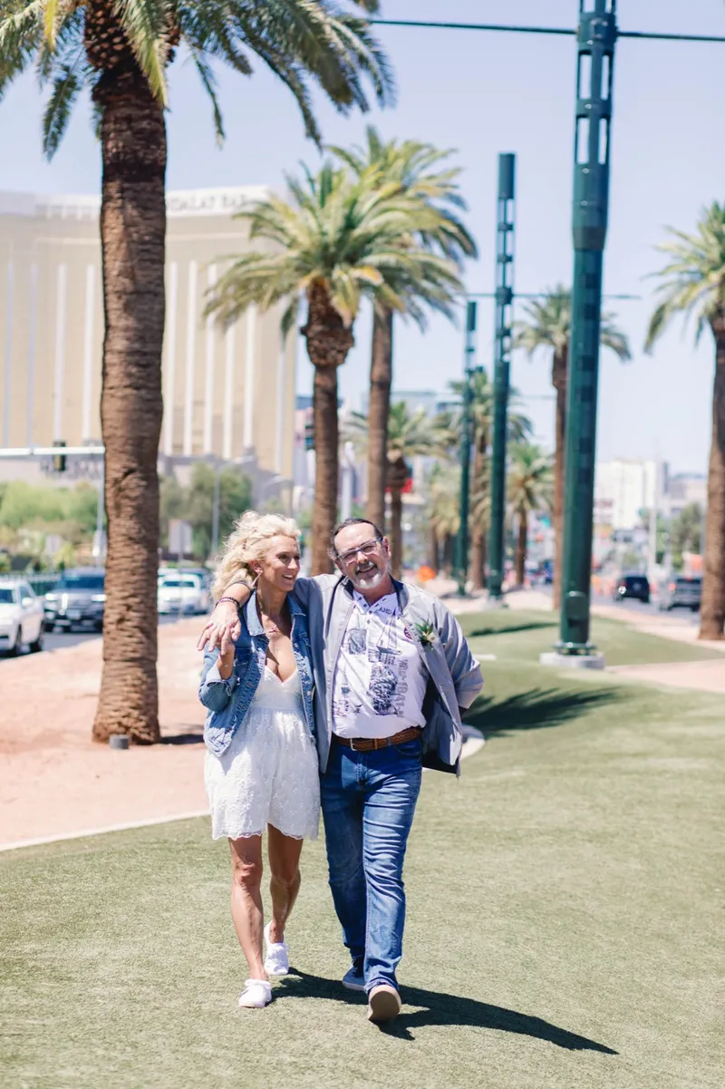 Couple walking together along the palm lined strip after their ceremony