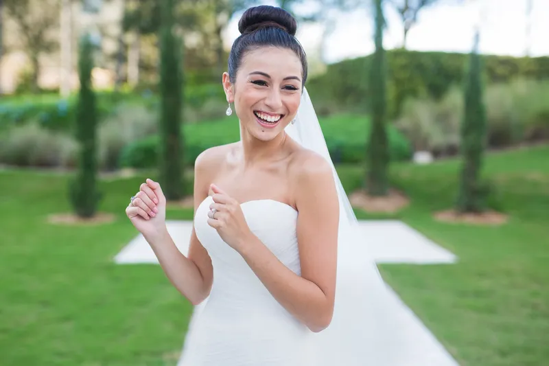 Bride laughing while holding her bouquet outdoors