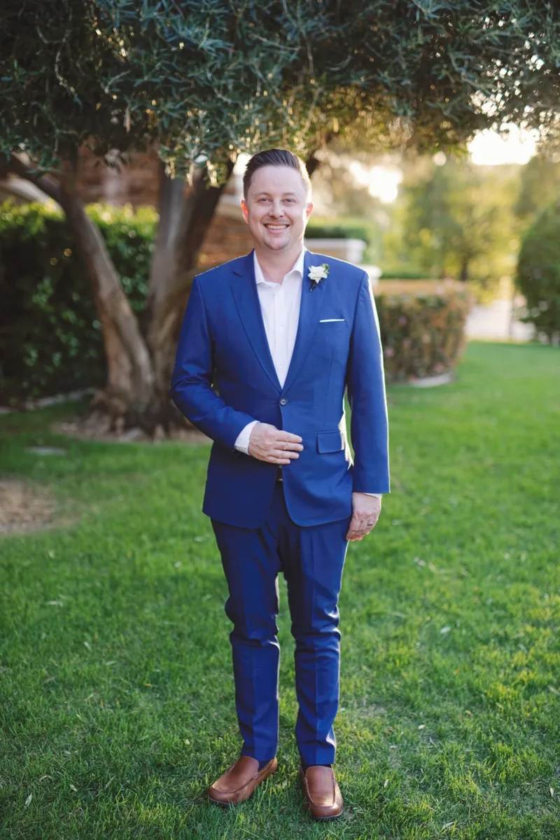 Groom standing on the lawn in a cobalt blue suit with a white boutonniere