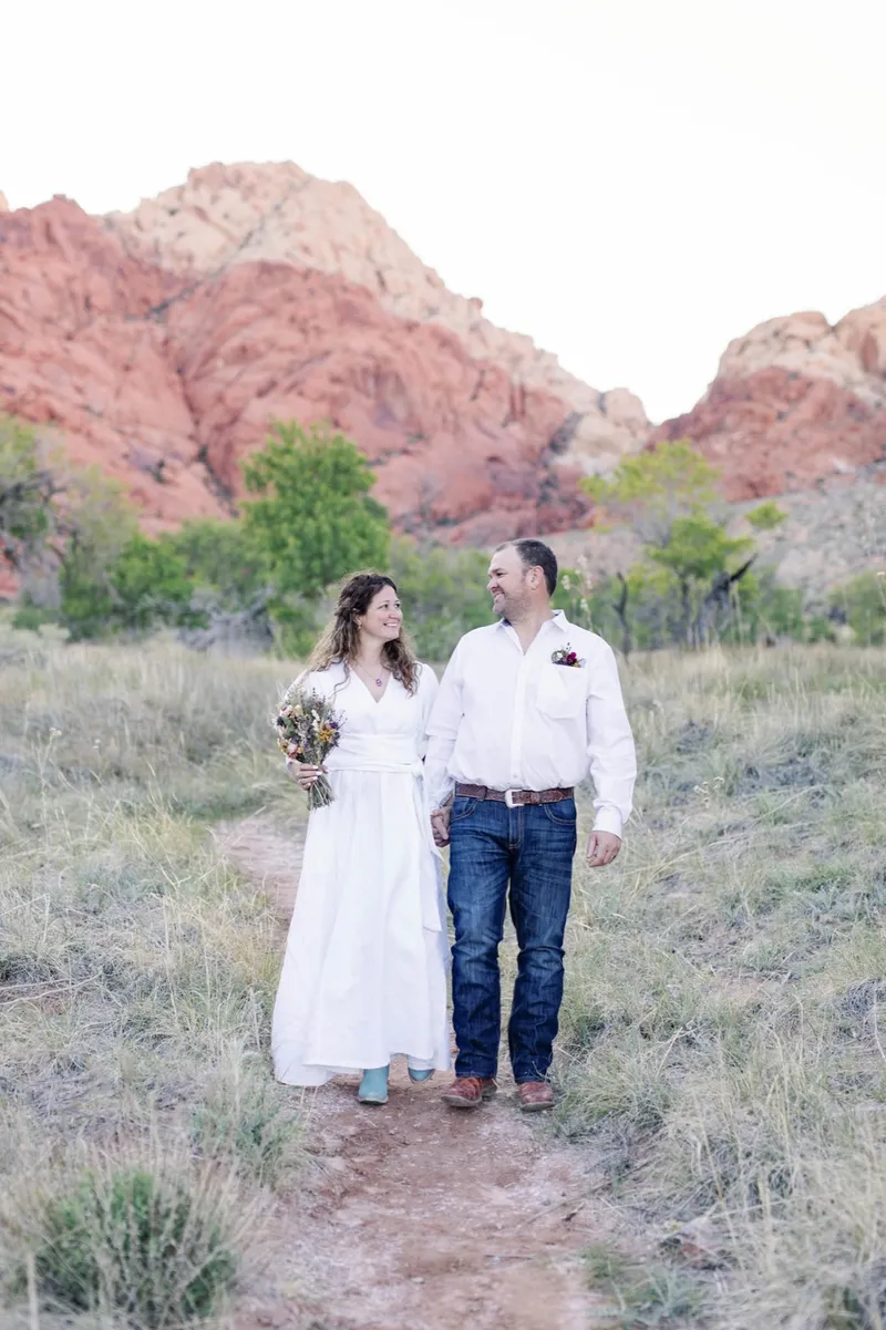 A bride and groom standing together in front of the red cliffs at Red Rock Canyon