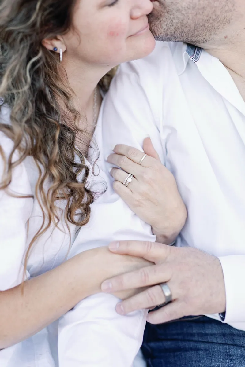 Close view of the couple's hands resting together with both wedding rings showing