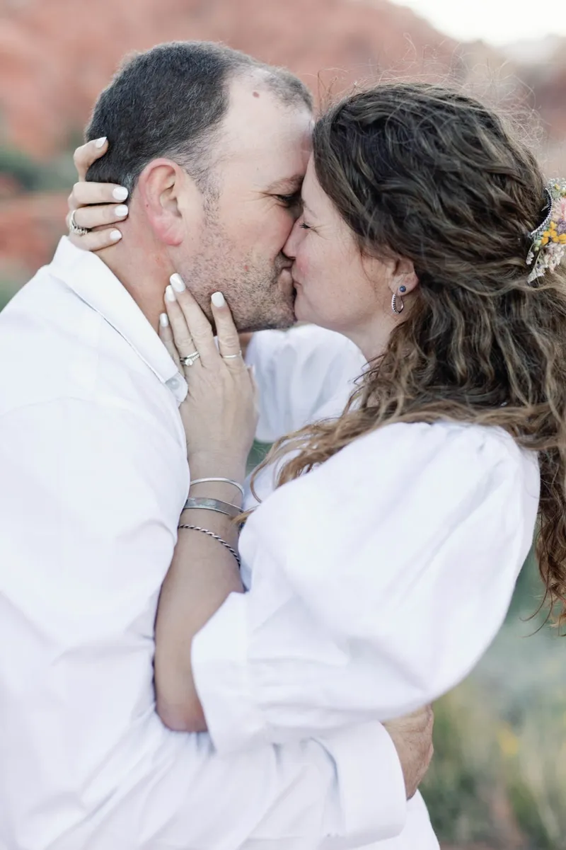 Groom kissing his bride with her hand resting against his face
