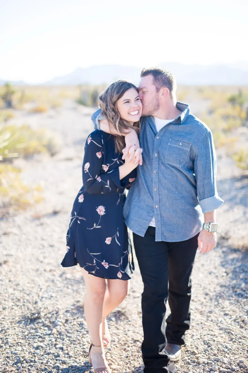 Couple walking a gravel wash together, her in a navy floral dress and him in a chambray shirt