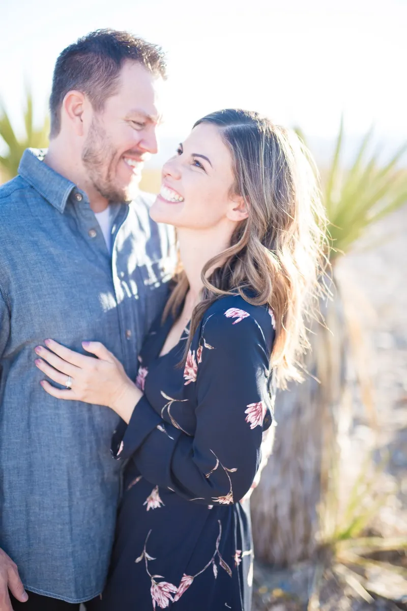 Backlit portrait of a laughing couple with a yucca and pale sky behind them