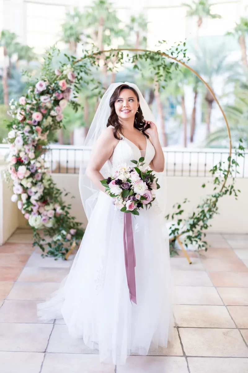 Bride standing inside the circular floral arch holding her bouquet