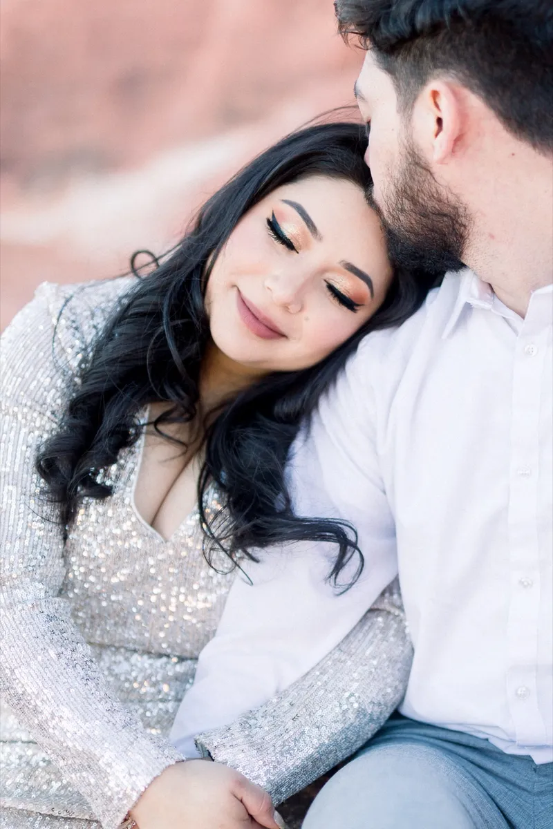 Woman resting her head on her fiance's shoulder with her eyes closed as they sit close together