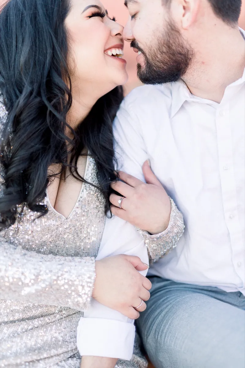 Couple laughing with their faces almost touching and her hand on his arm