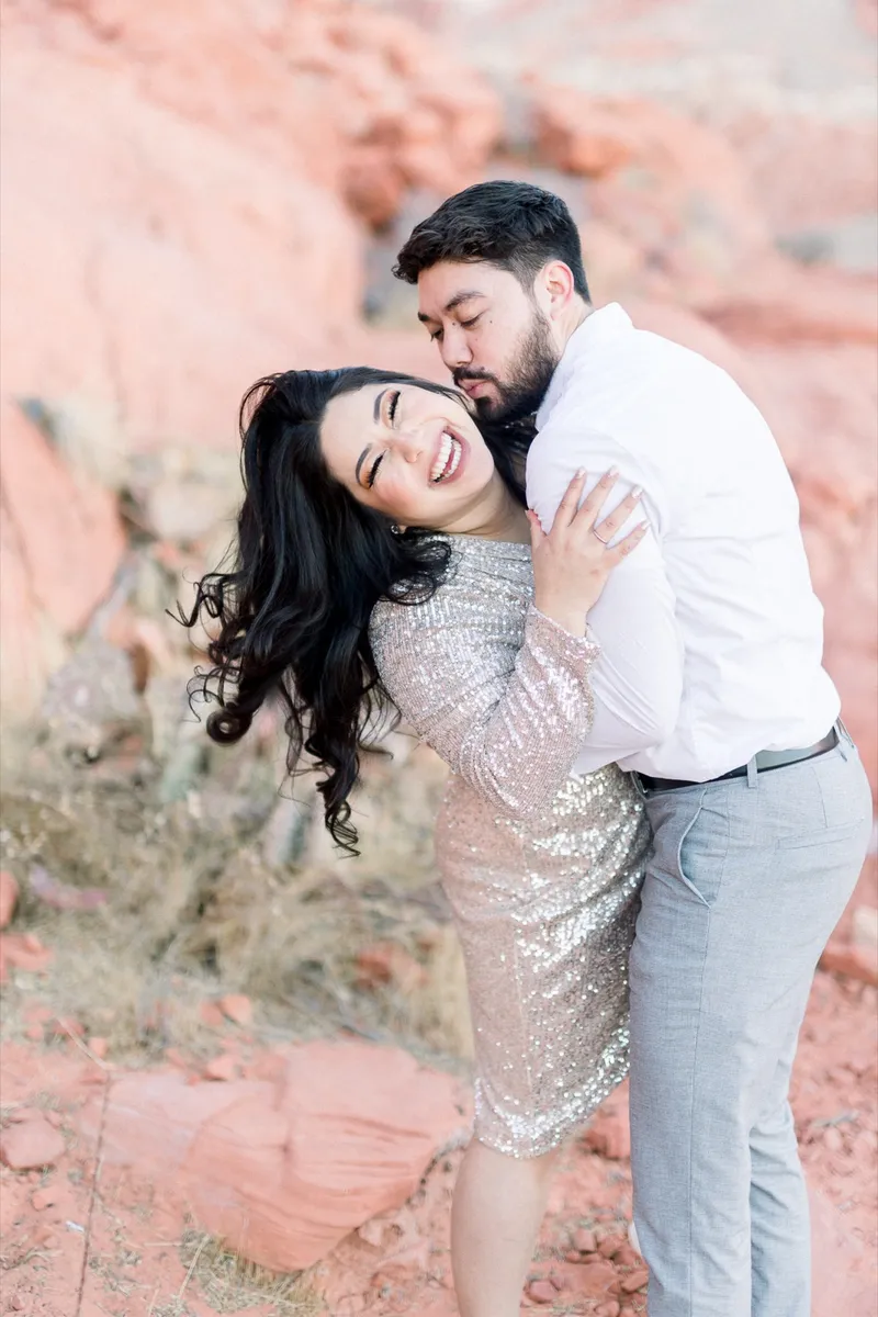Man kissing his fiancee's cheek as she laughs with her eyes closed