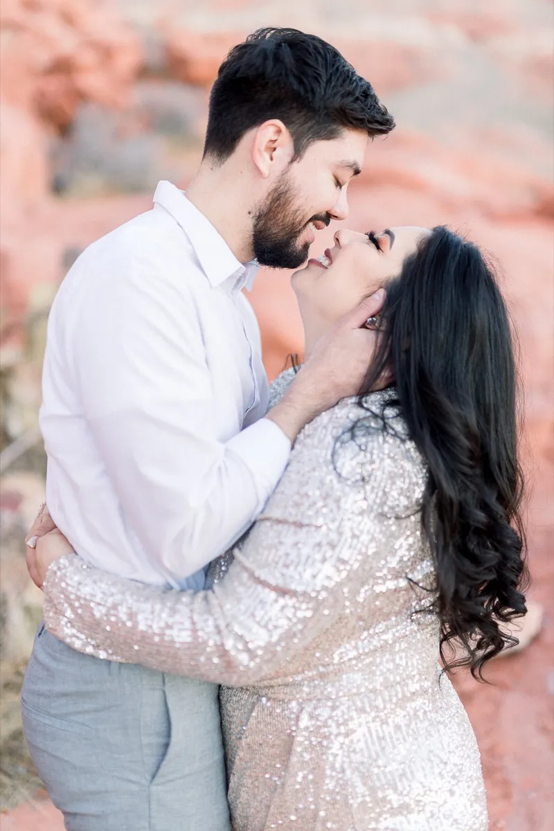 Couple about to kiss with his hand at her jaw and red rock filling the background