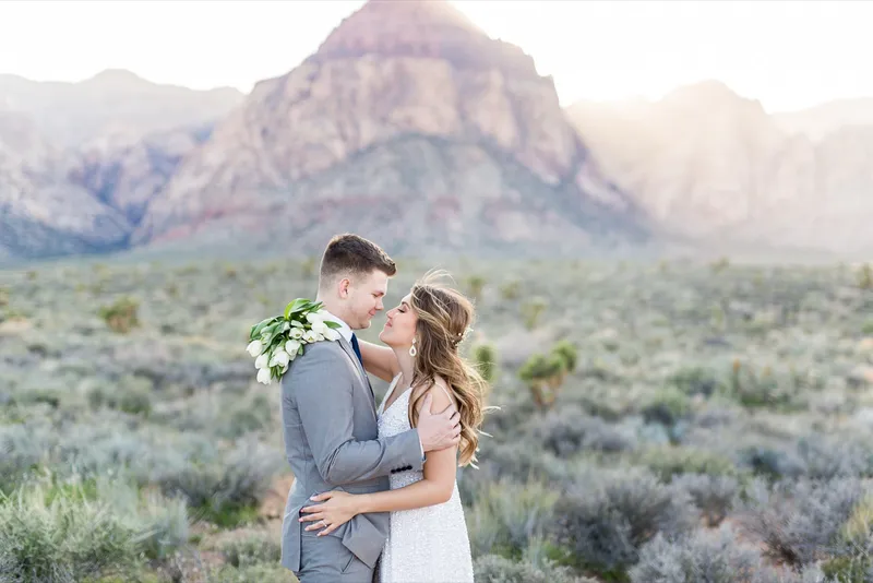 Bride and groom holding each other with her tulips at his shoulder and the peak behind