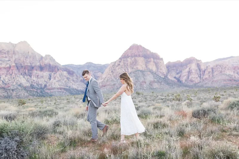 Couple walking a dirt path together with the red cliffs catching the last light