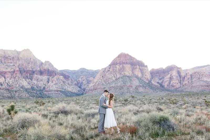 Couple kissing in the middle of an empty desert road with the red rock behind