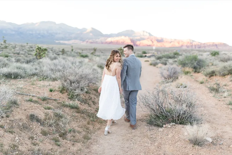 Bride and groom walking down the center of an empty road through the desert