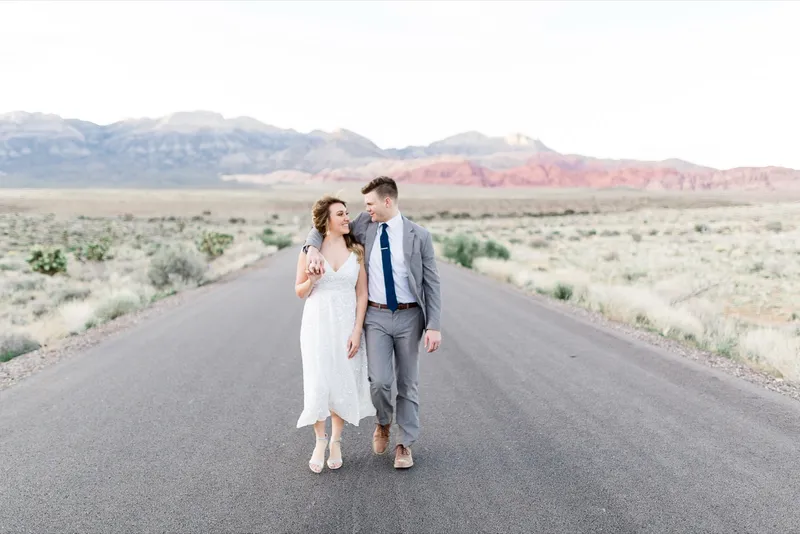 Couple kissing in the brush with the red and grey peak filling the frame behind