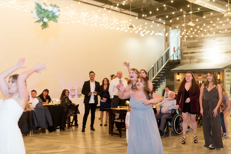 Guests dancing with their arms in the air on the open floor with the metal staircase behind them