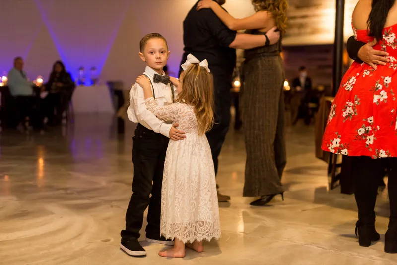 Two children dancing together on the floor while the adults dance behind them