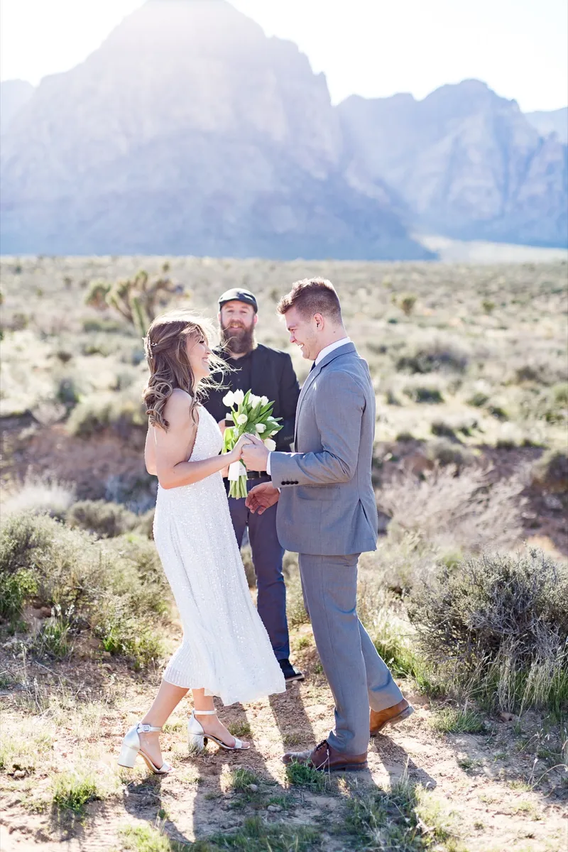 Bride and groom standing with their officiant for a small ceremony out in the open desert