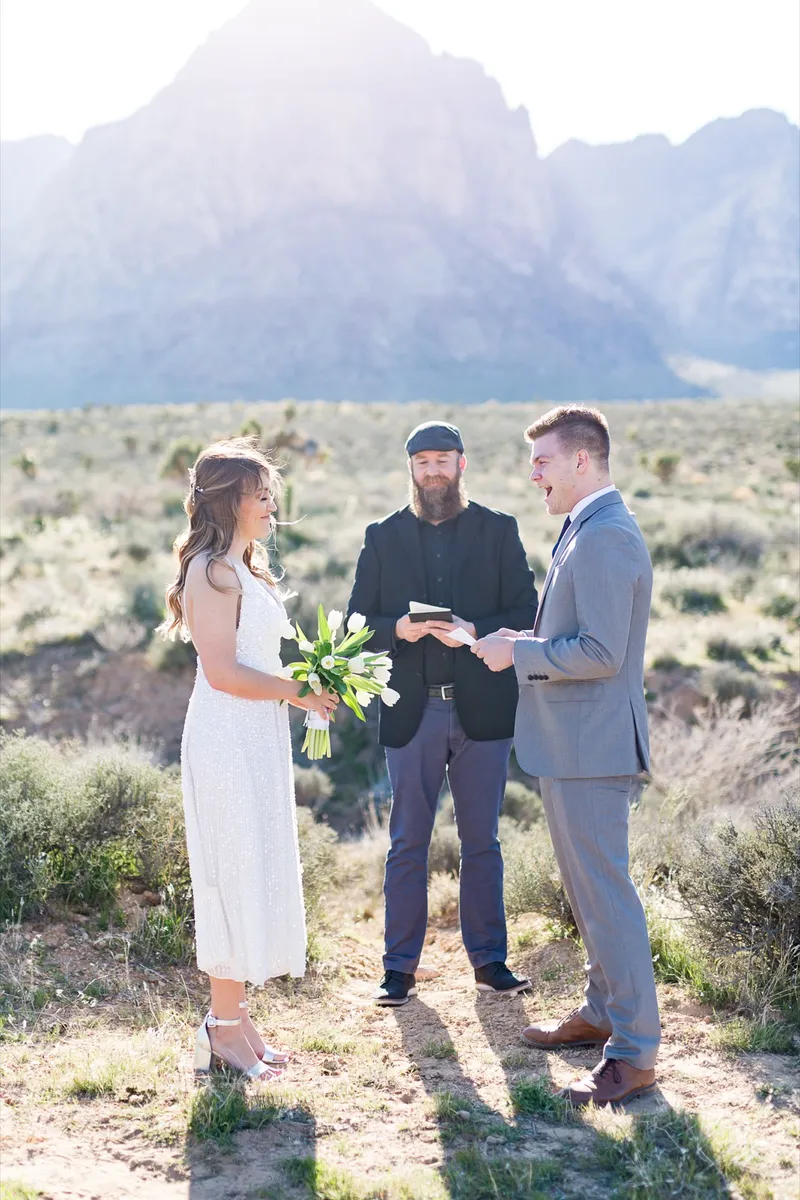 Bride and groom exchanging rings while their officiant holds the book open