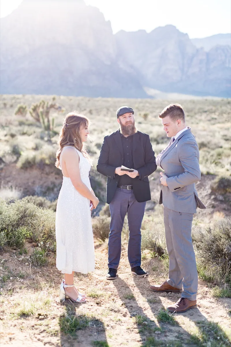 Officiant reading to the couple as they stand together in the desert brush