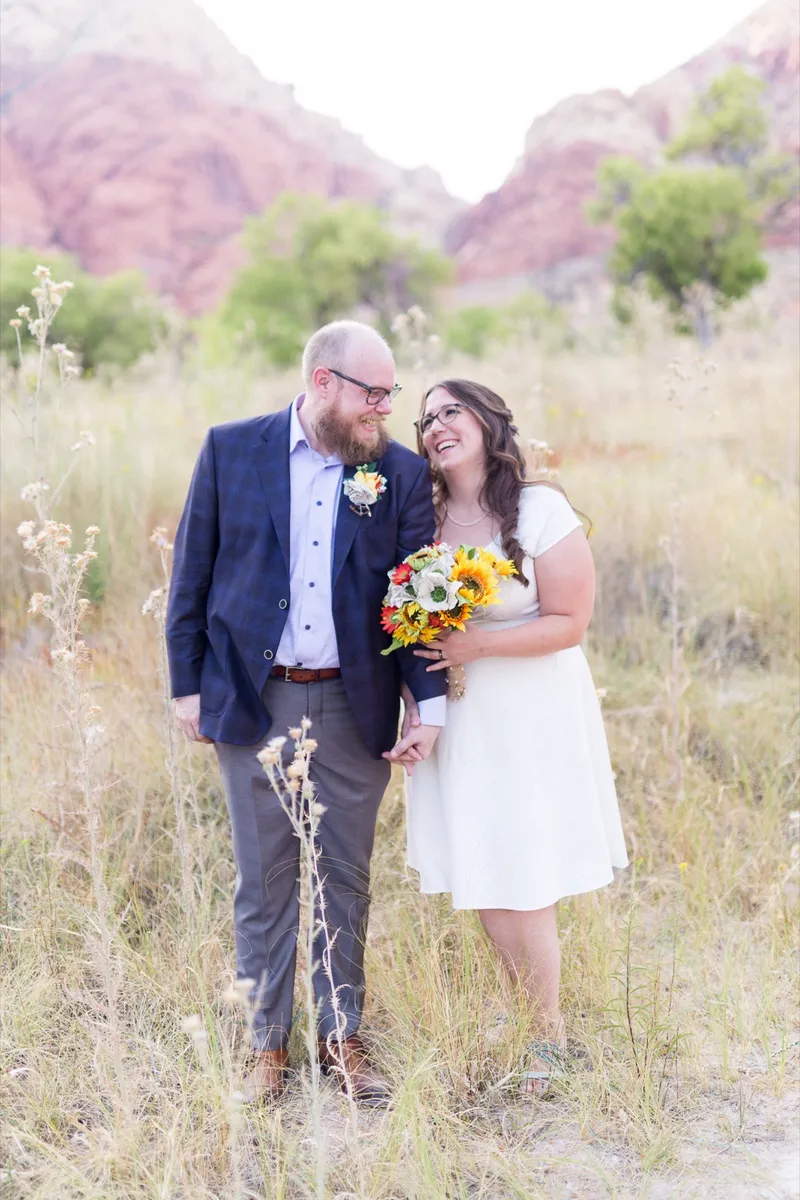 Bride and groom walking a desert path with their black and tan dog on a lead beside them