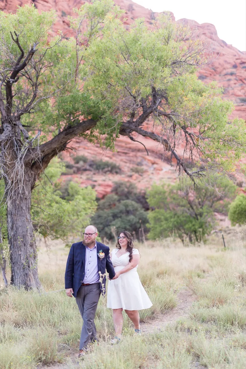 Couple standing together under a big desert tree with the grass tall around them