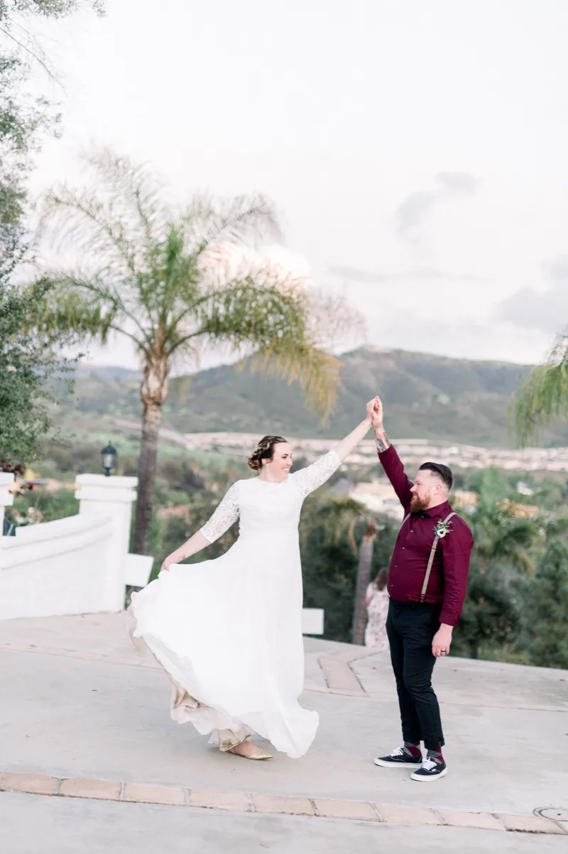 Groom twirling the bride on the driveway, her skirt flaring out around her